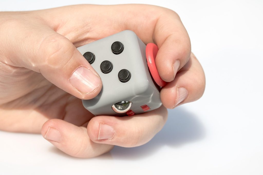 Tangan memegang Fidget Cube untuk meredakan stres dan meningkatkan fokus saat beraktivitas